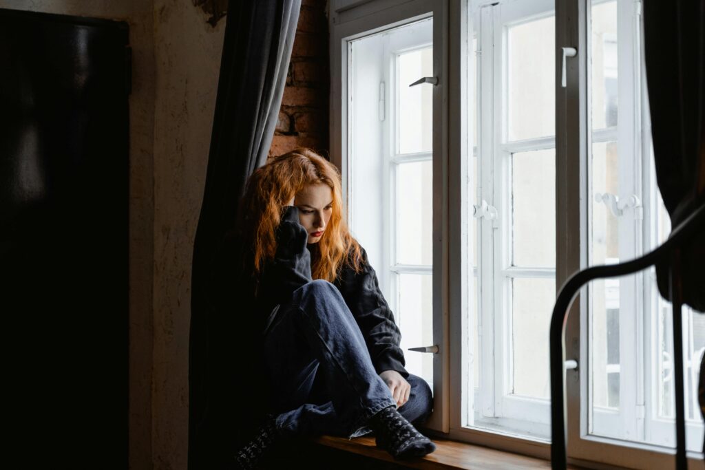 Girl dealing with difficult housemates sitting at window