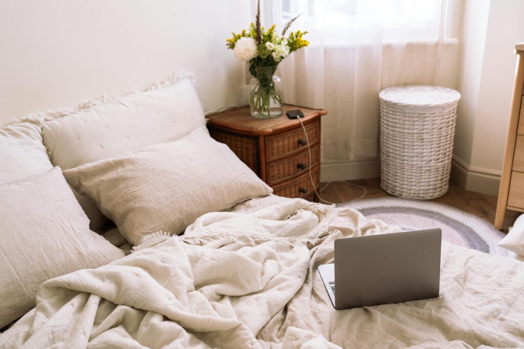cozy bedroom for alone time in a house share with bedside table with flowers on it and wicker washing basket
