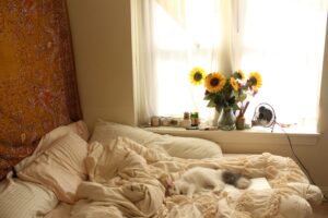 A cosy bedroom with sunflowers and a lounging cat. Providing inspo for renter-friendly bedroom ideas