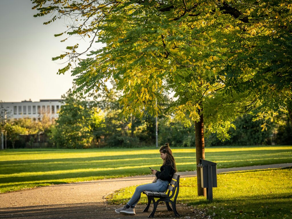 girl sitting alone in park on phone